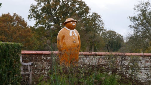 A statue of the Snowman™ coloured brown pictured in the garden at Baddesley Clinton, Warwickshire.